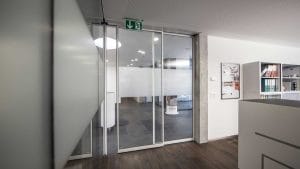 Ofis iç mekanı, cam kapı ve acil çıkış tabelası. Modern tasarımlı ve aydınlık bir ofis girişi.